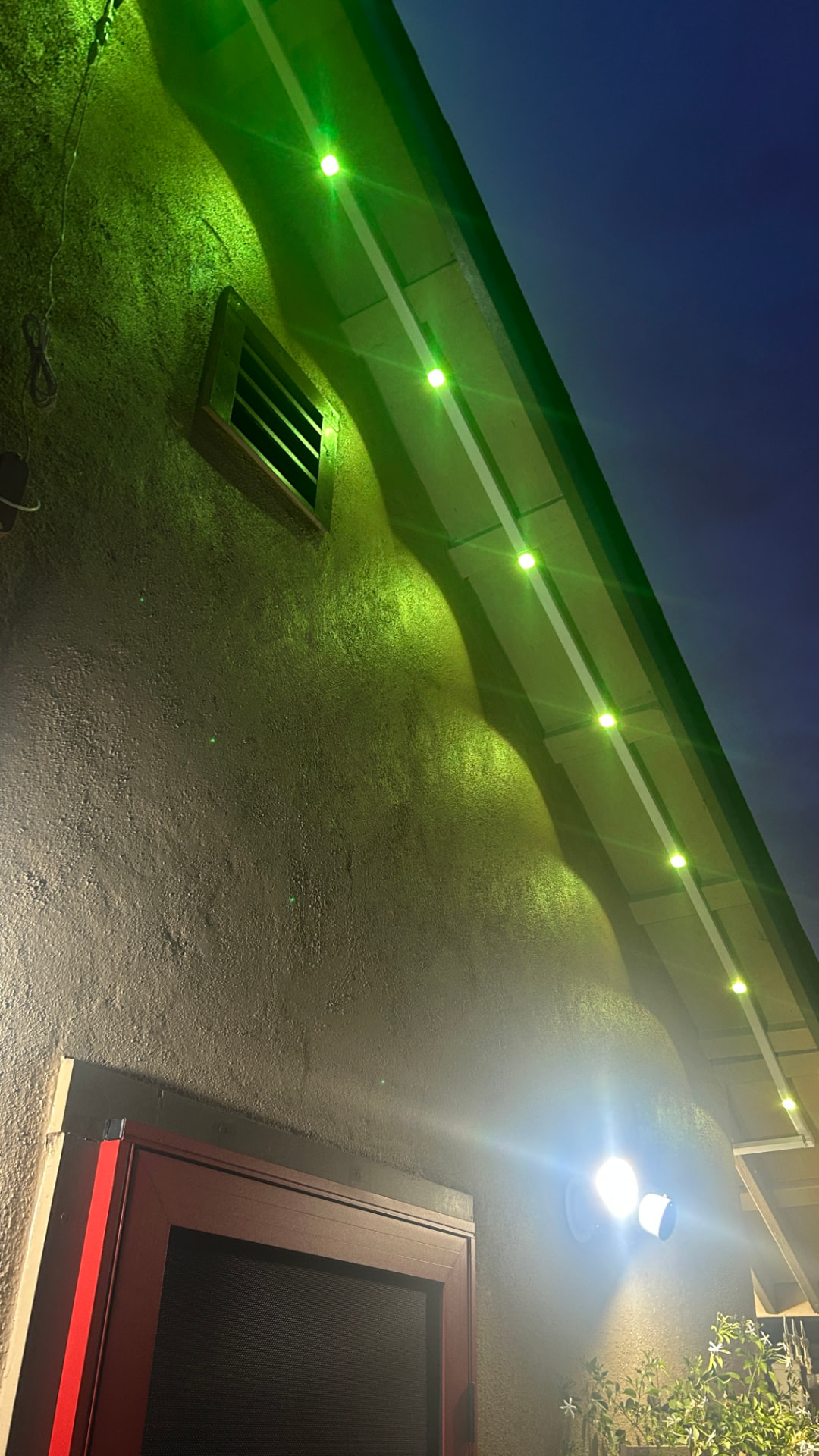 Home roofline at night lit with bright green permanent LED eave lighting