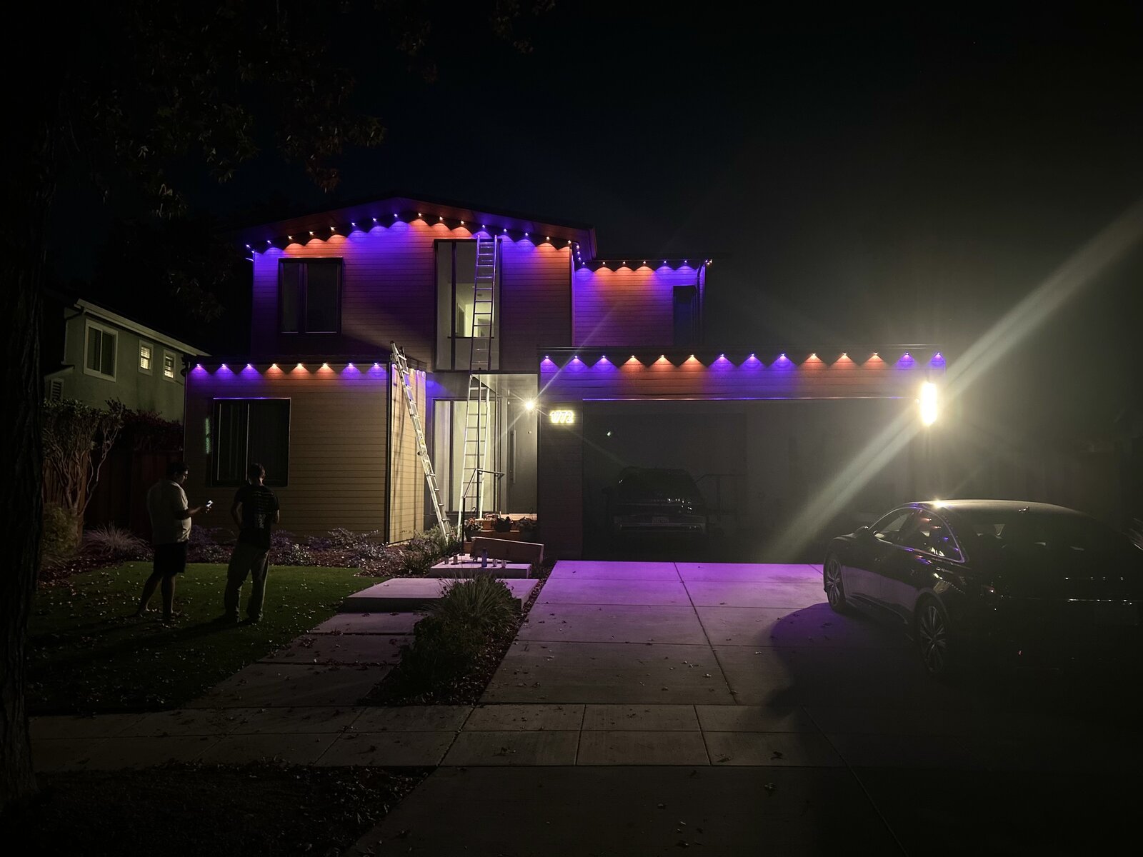 Modern two-story home at night with color-changing red, purple and orange permanent LED roofline lighting